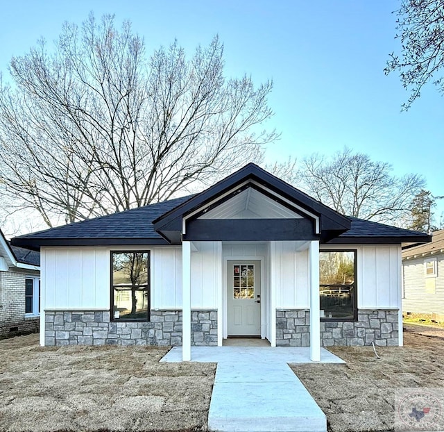 view of front of home featuring stone siding, board and batten siding, and roof with shingles