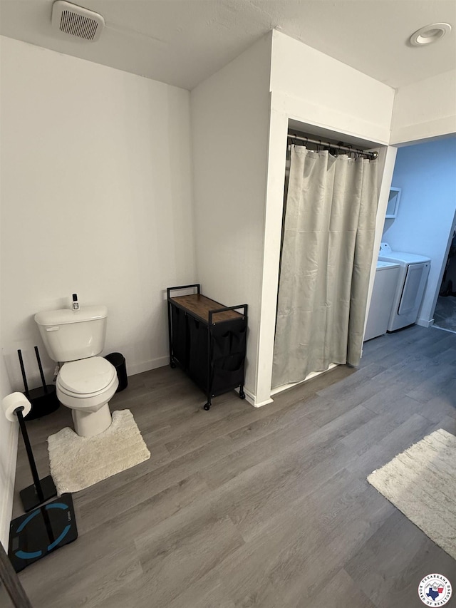 5440 Calico Duck Rd, Texarkana, AR 71854 - full bathroom featuring washer and dryer, wood finished floors, and curtained shower