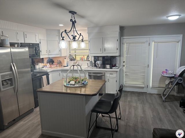 5440 Calico Duck Rd, Texarkana, AR 71854 - kitchen featuring appliances with stainless steel finishes, white cabinetry, dark wood finished floors, a center island, and hanging light fixtures