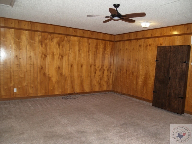 7311 Shilling Cir, Texarkana, TX 75503 - unfurnished room featuring ceiling fan, carpet flooring, wooden walls, and a textured ceiling