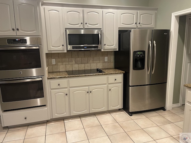 7311 Shilling Cir, Texarkana, TX 75503 - kitchen featuring stainless steel appliances, dark stone counters, decorative backsplash, light tile patterned floors, and white cabinetry