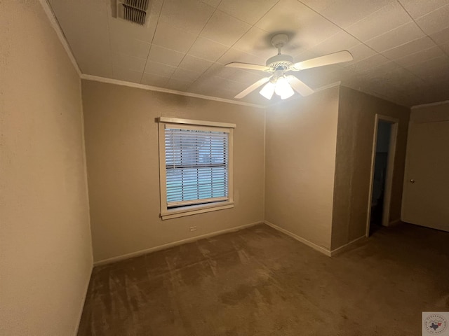 empty room featuring ceiling fan, dark carpet, and ornamental molding