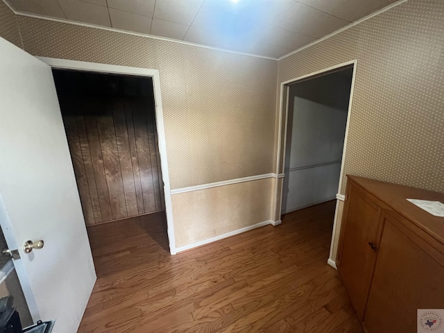 interior space with wood walls, light hardwood / wood-style flooring, and ornamental molding