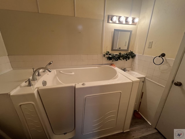 bathroom featuring hardwood / wood-style flooring and a tub to relax in