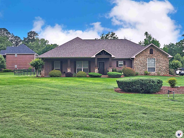 single story home with roof with shingles, a front lawn, and stone siding