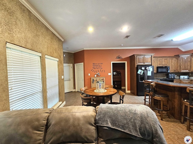 living area with light tile patterned floors, baseboards, ornamental molding, and visible vents