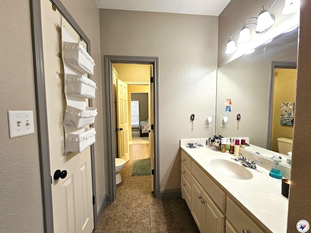 bathroom with a textured wall, tile patterned flooring, vanity, toilet, and baseboards