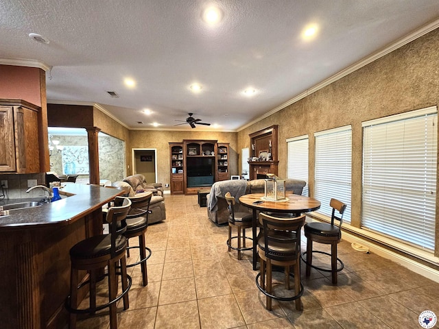 dining area with ornamental molding, decorative columns, ceiling fan, and light tile patterned flooring