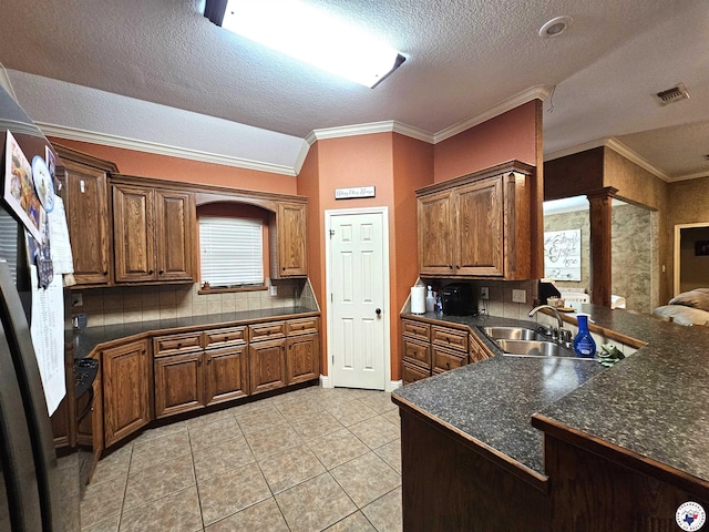 kitchen with ornamental molding, dark countertops, ornate columns, a sink, and light tile patterned floors