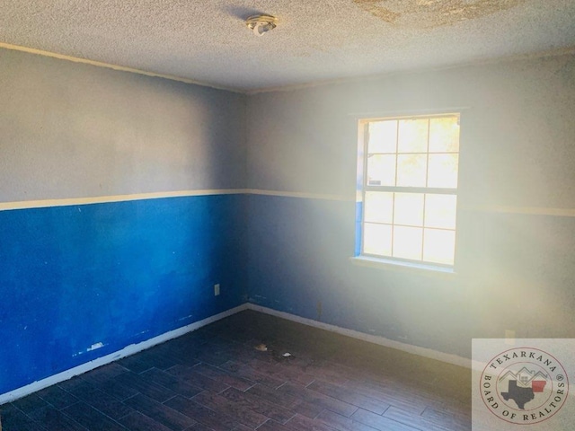 spare room featuring dark wood-type flooring and a textured ceiling