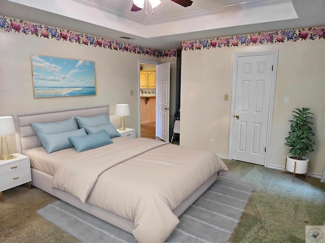 carpeted bedroom with ensuite bathroom, ceiling fan, ornamental molding, and a raised ceiling