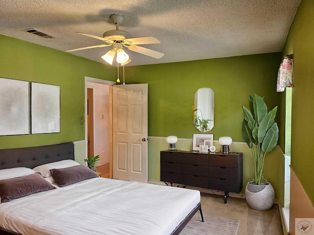 bedroom with light carpet, a textured ceiling, and ceiling fan