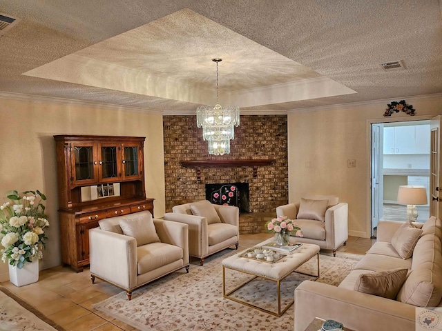 living room featuring ornamental molding, light tile patterned flooring, a brick fireplace, a raised ceiling, and a chandelier