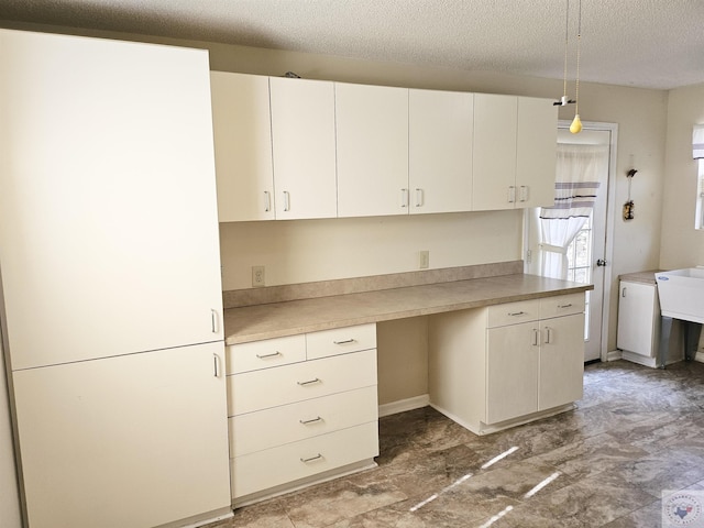 kitchen featuring pendant lighting, white cabinets, and a textured ceiling