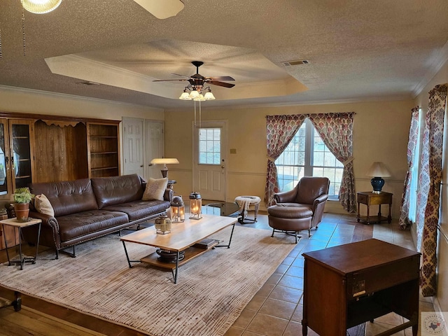 tiled living room featuring crown molding, ceiling fan, a textured ceiling, and a tray ceiling