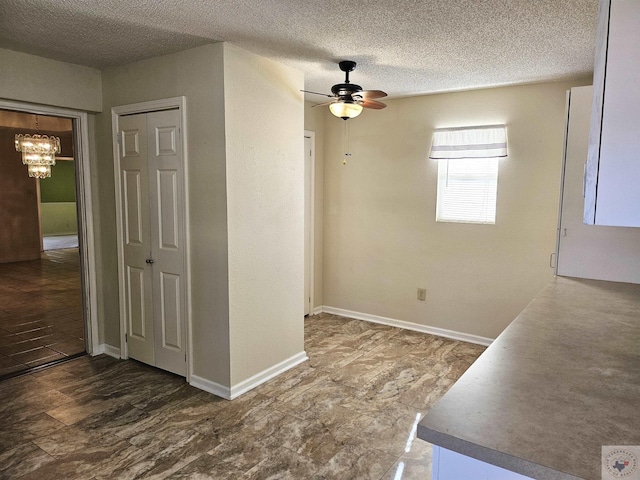 interior space with ceiling fan with notable chandelier and a textured ceiling