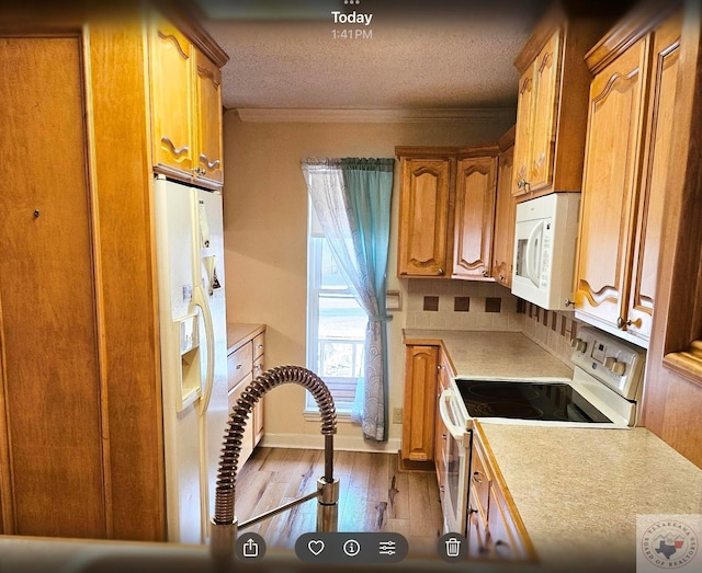 kitchen featuring a textured ceiling, ornamental molding, white appliances, light hardwood / wood-style floors, and backsplash