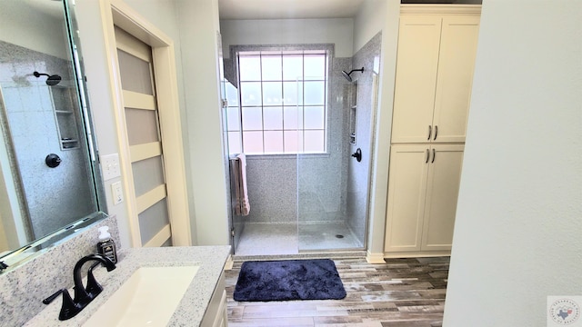 bathroom featuring hardwood / wood-style flooring, vanity, and tiled shower