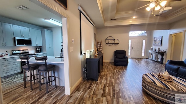 living room with dark hardwood / wood-style floors, ornamental molding, and a raised ceiling