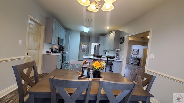 dining area with dark wood-type flooring and an inviting chandelier