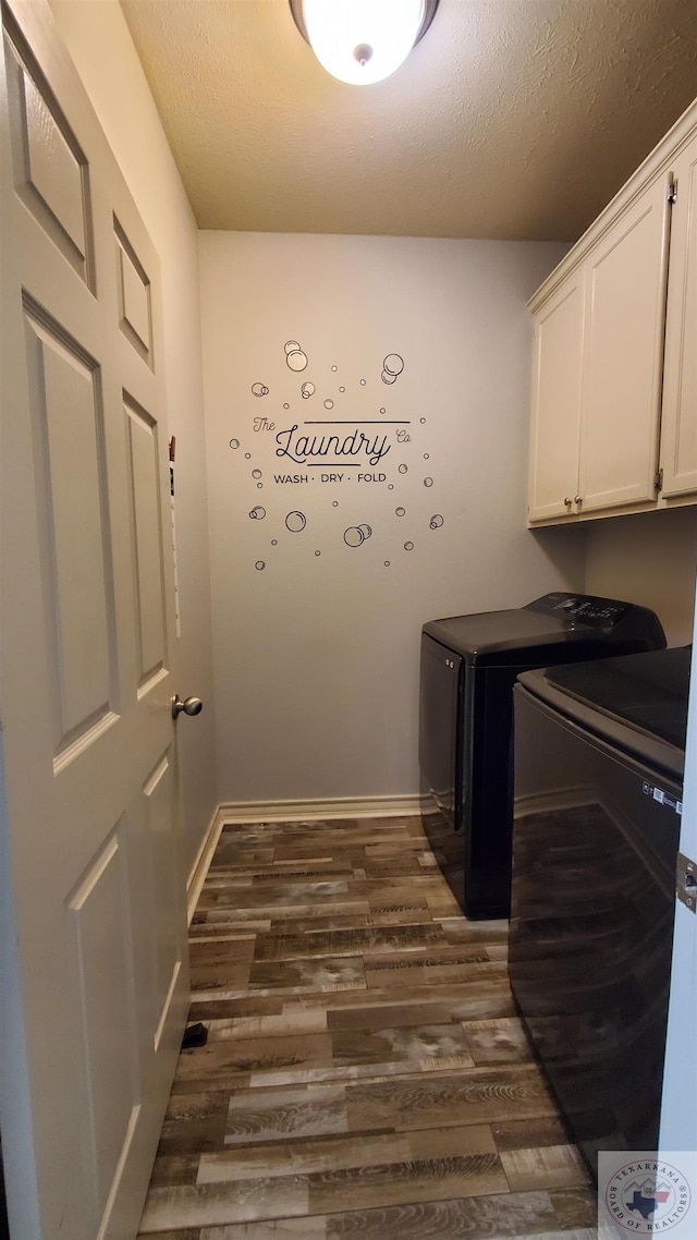 laundry area with cabinets, washing machine and dryer, dark wood-type flooring, and a textured ceiling