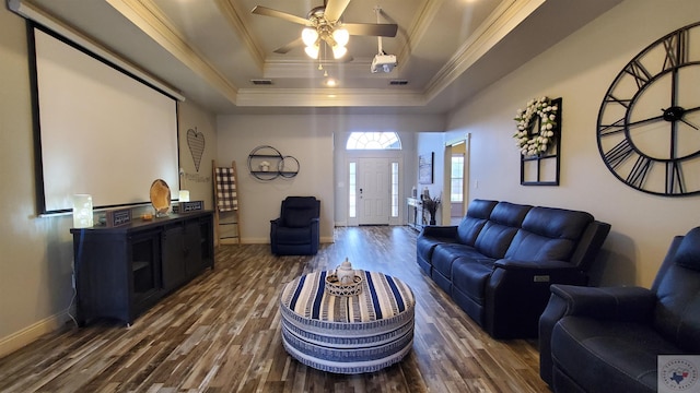 living room featuring dark hardwood / wood-style flooring, ornamental molding, a raised ceiling, and ceiling fan