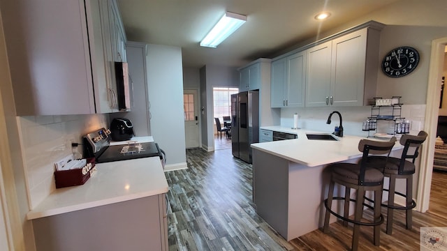 kitchen with stainless steel appliances, sink, decorative backsplash, and kitchen peninsula