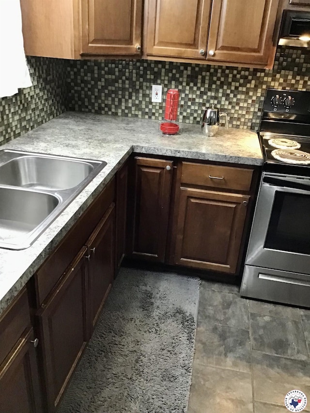 kitchen featuring light countertops, range with electric stovetop, decorative backsplash, and a sink