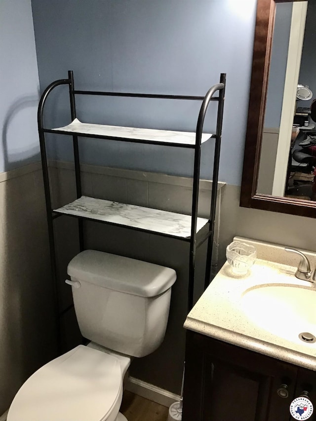 half bath with wood finished floors, vanity, and toilet