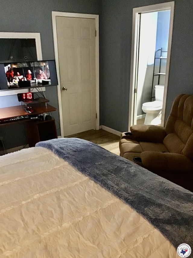 bedroom featuring baseboards, ensuite bathroom, and wood finished floors