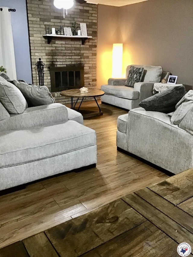 living area featuring a brick fireplace and wood finished floors