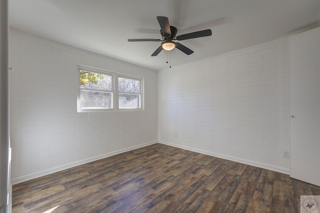 spare room featuring brick wall, ceiling fan, and dark hardwood / wood-style flooring