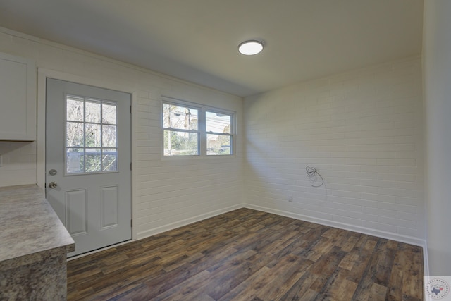 interior space with brick wall and dark hardwood / wood-style flooring