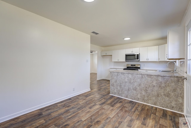 kitchen featuring white cabinets, dark wood-type flooring, stainless steel appliances, decorative backsplash, and sink