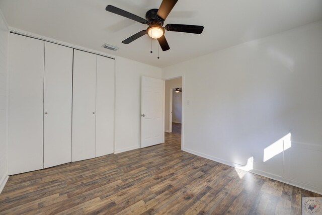 unfurnished bedroom featuring ceiling fan, dark hardwood / wood-style flooring, and a closet