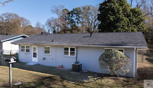 rear view of house with cooling unit and a lawn