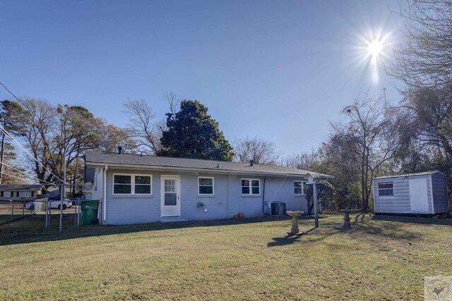 rear view of house featuring cooling unit, a shed, and a lawn