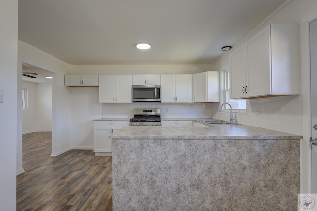 kitchen featuring appliances with stainless steel finishes, sink, white cabinets, dark wood-type flooring, and decorative backsplash