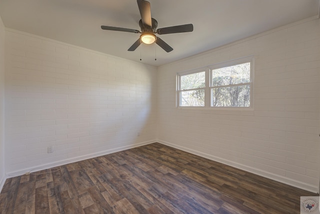 empty room featuring ceiling fan, brick wall, and dark hardwood / wood-style flooring