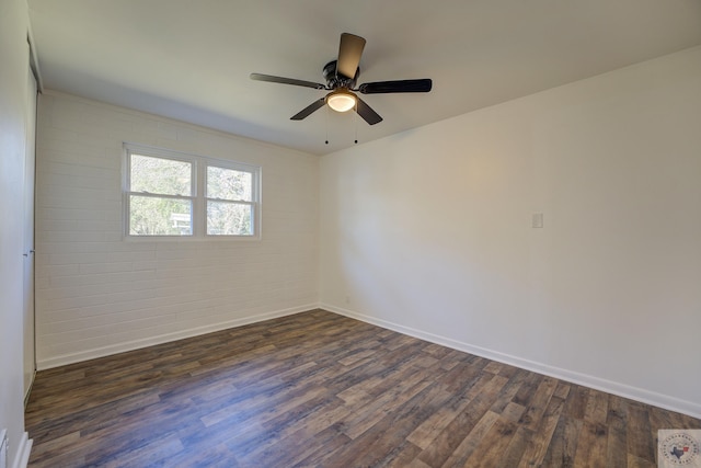 spare room with dark wood-type flooring, brick wall, and ceiling fan