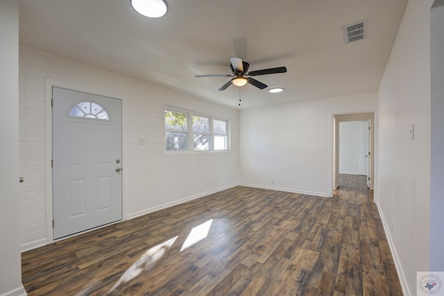 entrance foyer with ceiling fan, brick wall, and dark hardwood / wood-style floors