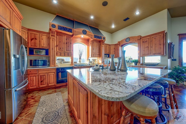 kitchen featuring tile patterned flooring, a large island, light stone countertops, a breakfast bar area, and stainless steel appliances