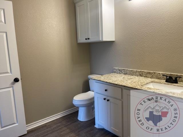 bathroom with vanity, toilet, and hardwood / wood-style floors