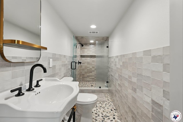 10 Jetty Steel Dr, Murfreesboro, AR 71958 - bathroom with tile walls, a shower stall, a sink, toilet, and a wainscoted wall
