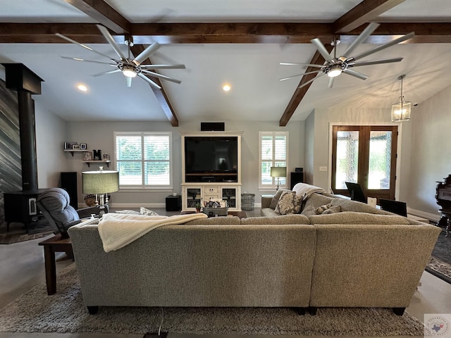 living room featuring ceiling fan, vaulted ceiling with beams, and a wood stove