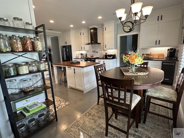 kitchen featuring pendant lighting, wall chimney exhaust hood, wooden counters, white cabinetry, and decorative backsplash