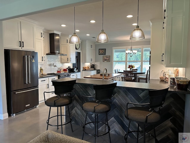 kitchen with high quality fridge, wall chimney range hood, pendant lighting, a breakfast bar, and backsplash