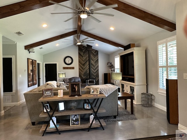 living room featuring ceiling fan, a wood stove, and vaulted ceiling with beams