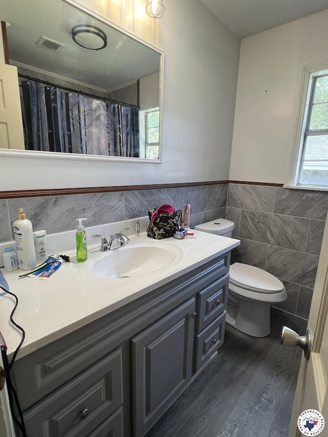 4320 Jefferson Ave, Texarkana, AR 71854 - full bathroom featuring tile walls, vanity, a wainscoted wall, wood finished floors, and curtained shower