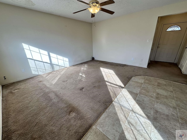 spare room with light colored carpet, a textured ceiling, and ceiling fan